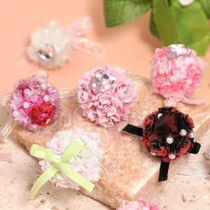 Detailed close-up of colorful floral fabric charms with pearls and ribbon on stone