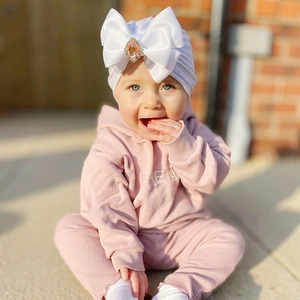 Detail of baby turban with large white satin bow and pink rhinestone on ribbed knit hoodie