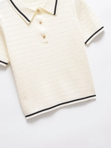 Close-up of cream knit Polo shirt with cable texture and gold embossed buttons