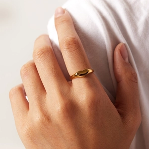 Nahaufnahme eines minimalistischen goldenen Herzrings am Finger mit weichem Hintergrund