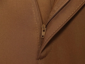 Makroaufnahme der braunen Twill-Stoffstruktur und des hochwertigen Metallreißverschlusses
