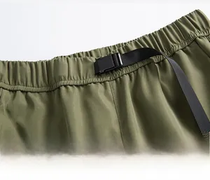 Detalle de la hebilla ajustable y la cintura elástica del pantalón cargo verde militar