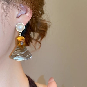 Close-up of fan-shaped marble resin earring with amber block and pearl on model