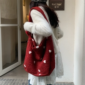 Detail of red plush tote bag with white heart patterns and fuzzy texture for winter