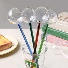 Close-up of colorful glass stir sticks with round heads and long handles in a cup