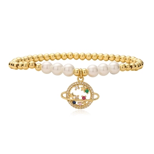 Bracelet en perles dorées avec perles blanches et un pendentif Saturne serti de zircons