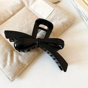 Macro shot of large glossy black ribbon claw clip for hair styling on linen background