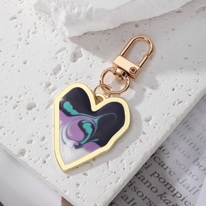 Detail of a heart-shaped gold alloy keychain featuring purple fluid art on white rock