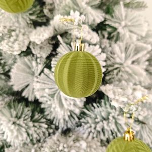 Détail de boules de Noël vertes floquées avec texture ondulée sur branches enneigées