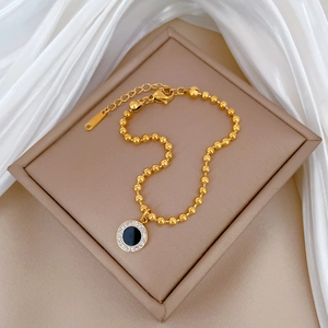Detail of gold titanium steel necklace with black agate pendant on silk background