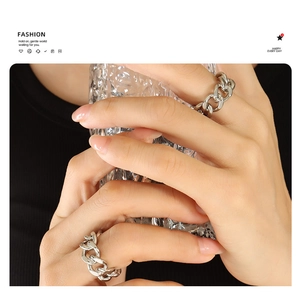 Close-up of minimalist silver chain rings on hands holding a clear textured glass