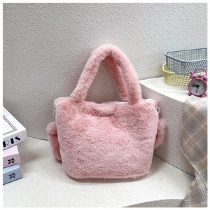 Detail of pink faux fur tote bag showing plush texture and decorative pom-pom accessory