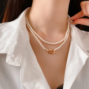 Close-up of double-layer pearl necklace with interlocking gold rings on a model