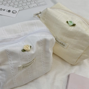 Detailed close-up of textured knit cosmetic bags with elegant ribbon rose accents