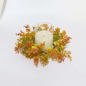 Close-up of orange eucalyptus leaf candle ring with a glass holder and white candle