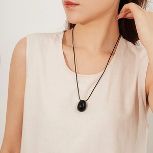 Vue détaillée du pendentif ovale en obsidienne noire sur un collier en cordon de cire