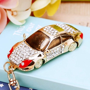Close-up of gold metal car keychain encrusted with crystals on a blue book