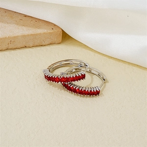 Detailed view of silver hoop earrings with channel-set rectangular red cubic zirconia stones