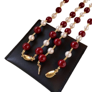 Collana vintage di perle rosse e bianche con distanziali dorati su tappeto nero