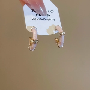 Close-up of C-shaped bamboo stud earrings with pink enamel and sparkling rhinestones