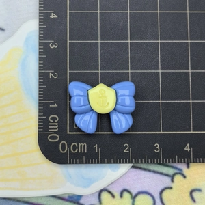 Close-up of blue resin bow with yellow anchor emblem on a measuring mat