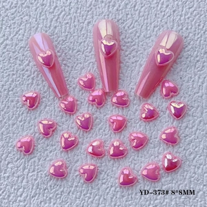 Macro shot of 8x8mm aurora pink heart resin nail art charms on white plush background