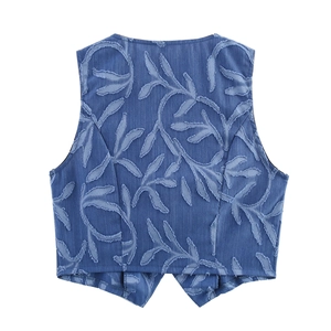 Detail of blue denim vest featuring textured fringe leaf patterns and a V-split hem design