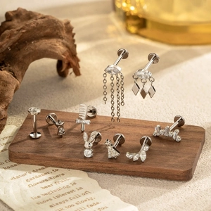 Titanium G23 flat back earrings with silver stars, crowns and charms on wood surface