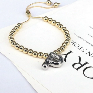Detail of adjustable gold beaded bracelet featuring a silver 3D balloon initial P charm