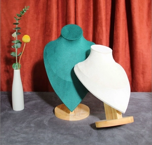 Detail of velvet necklace busts in dark green and beige on wooden stands with decor
