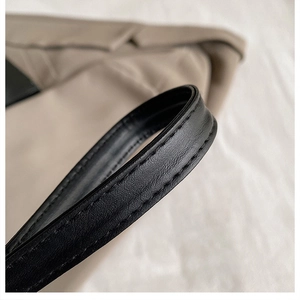 Close-up of premium stitching and texture on the beige and black leather handbag