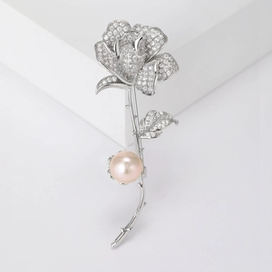 Détail macro d'une broche rose argentée avec zircons sertis et une perle rose