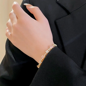 Detailed view of a gold bracelet featuring a pink square zircon on a model wrist