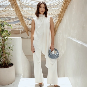 Detail of white sleeveless asymmetrical top paired with stylish blue woven handbag