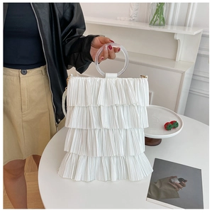 White tiered ruffle tote bag detail featuring transparent resin handle and layered fabric