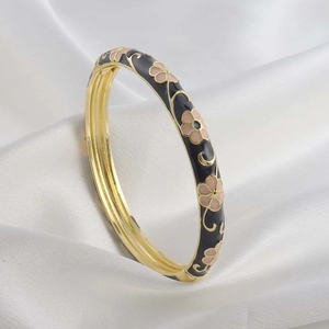 Detail of vintage enamel bangle with pink flowers on black coating and gold metal lining