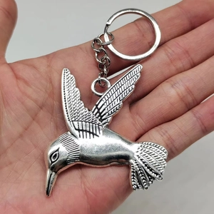 Vintage silver alloy hummingbird keychain with intricate feather details held by hand