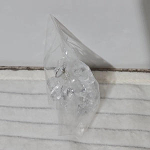Detailed close-up of acrylic pine cone Christmas ornaments in a clear packaging bag