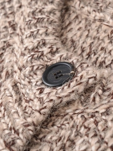 Macro detail of mixed brown knit fabric with a black button on the stylish vest