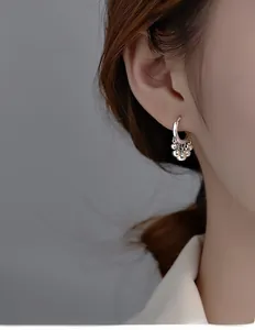 Detail view of silver tassel earrings with polished beads on a model side profile