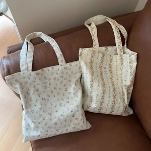 Floral cotton canvas tote bags in pink floral and orange stripe patterns on a sofa