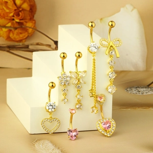 Detailed view of six gold-plated belly rings with sparkling zircon hearts and bows