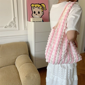 Detail of pink and white bubble texture shoulder bag worn by model in cozy indoor setting