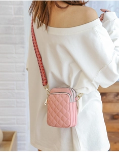 Pink quilted nylon crossbody phone bag with colorful woven strap shown on a female model