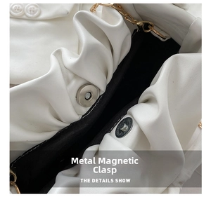 Detail shot of the white pleated cloud bag with magnetic snap closure and golden chain