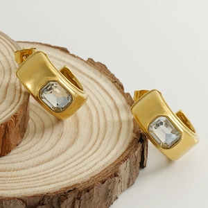 Boucles d'oreilles en C plaquées or 18K avec zircon central sur support en bois