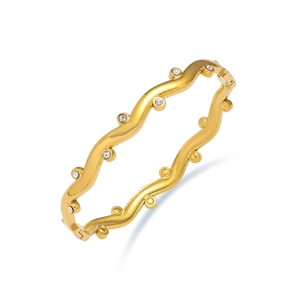 Detail of wavy golden titanium steel bracelet with sparkling zircons on white background