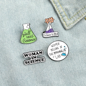 Set of 4 creative science enamel pins with funny quotes on light blue denim background