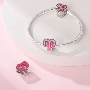 Macro detail of Aries heart charm with pink enamel on a silver snake chain bracelet