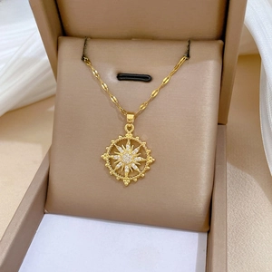 Detailed close-up of a gold starburst pendant necklace with cubic zirconia on silk cloth